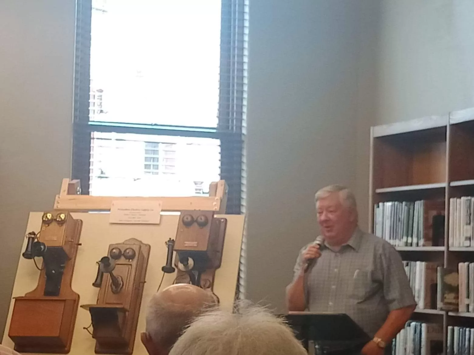 man speaks about old telephones on display next to him