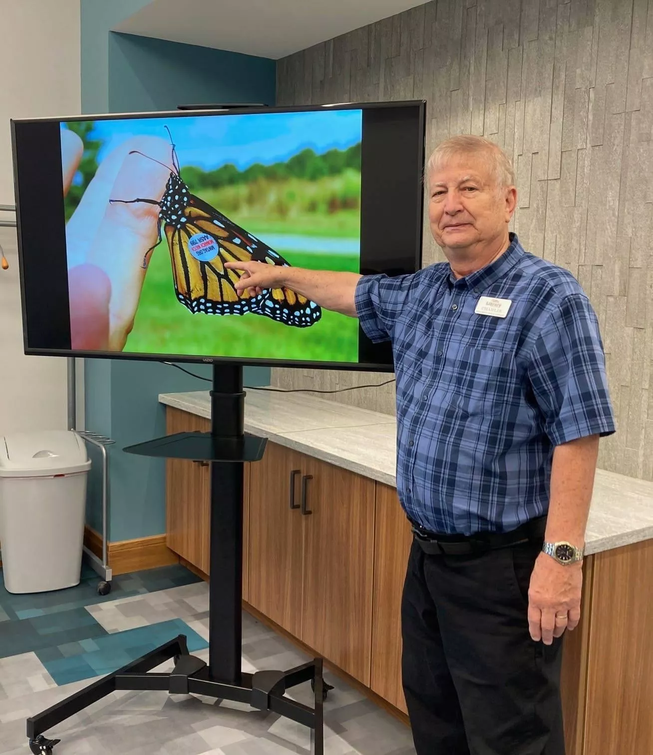 local man pointing at tv screen of monarch butterfly