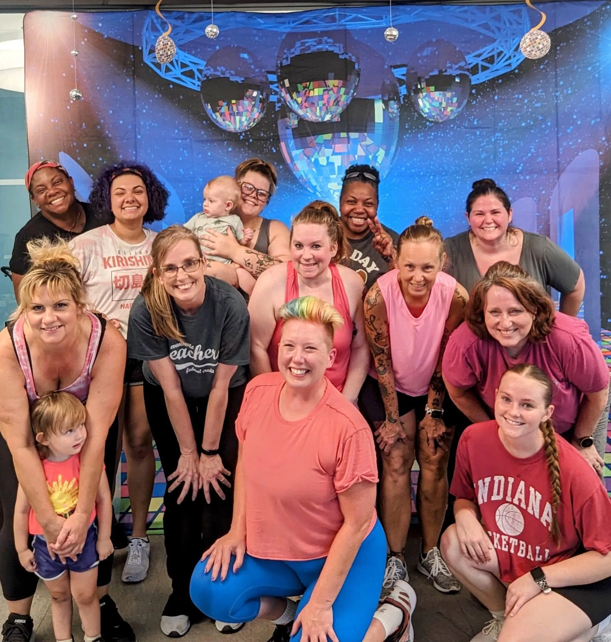 several people in exercise clothes in front of disco themed backdrop