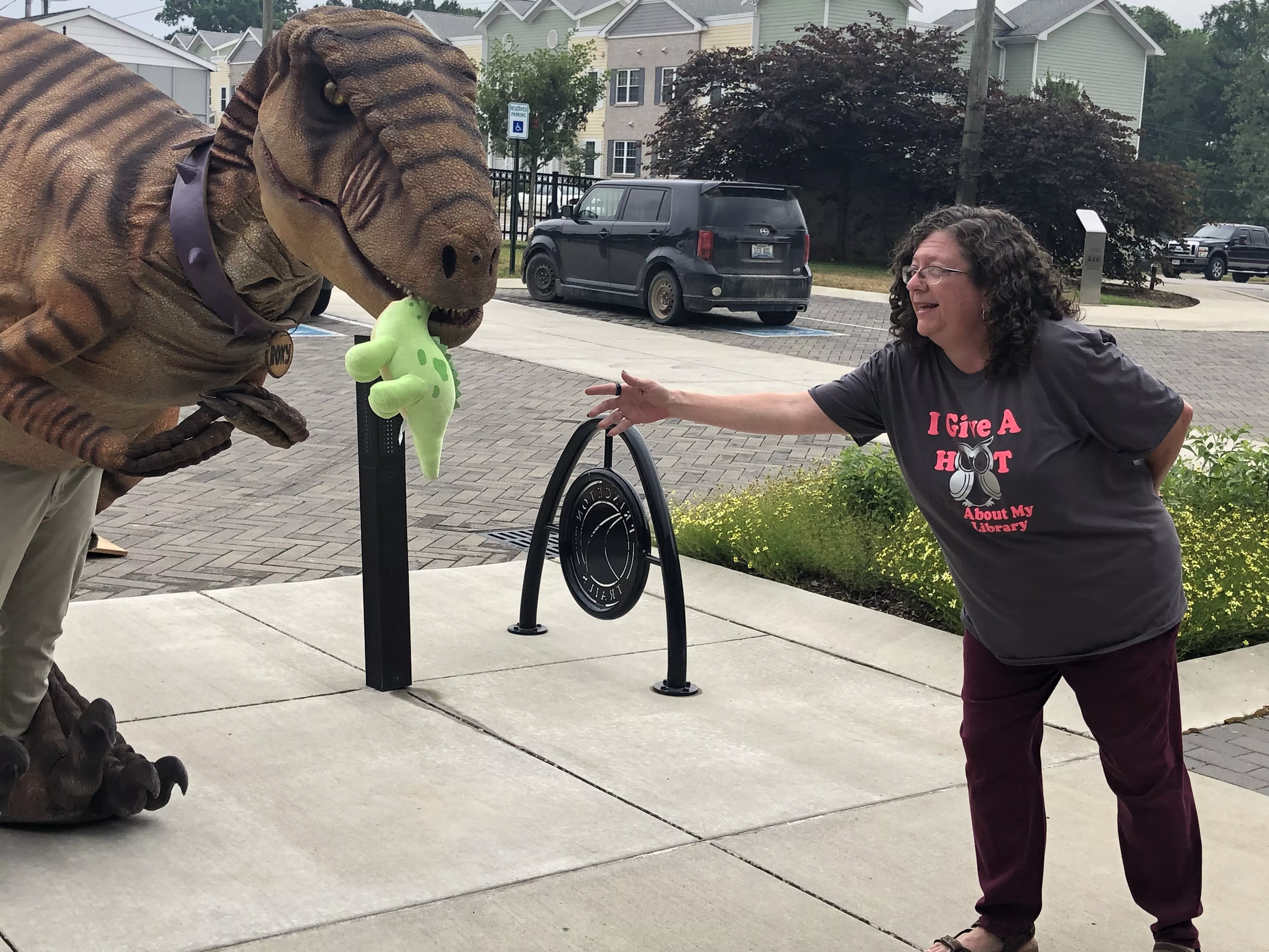 lady handing stuffed animal to dinosaur