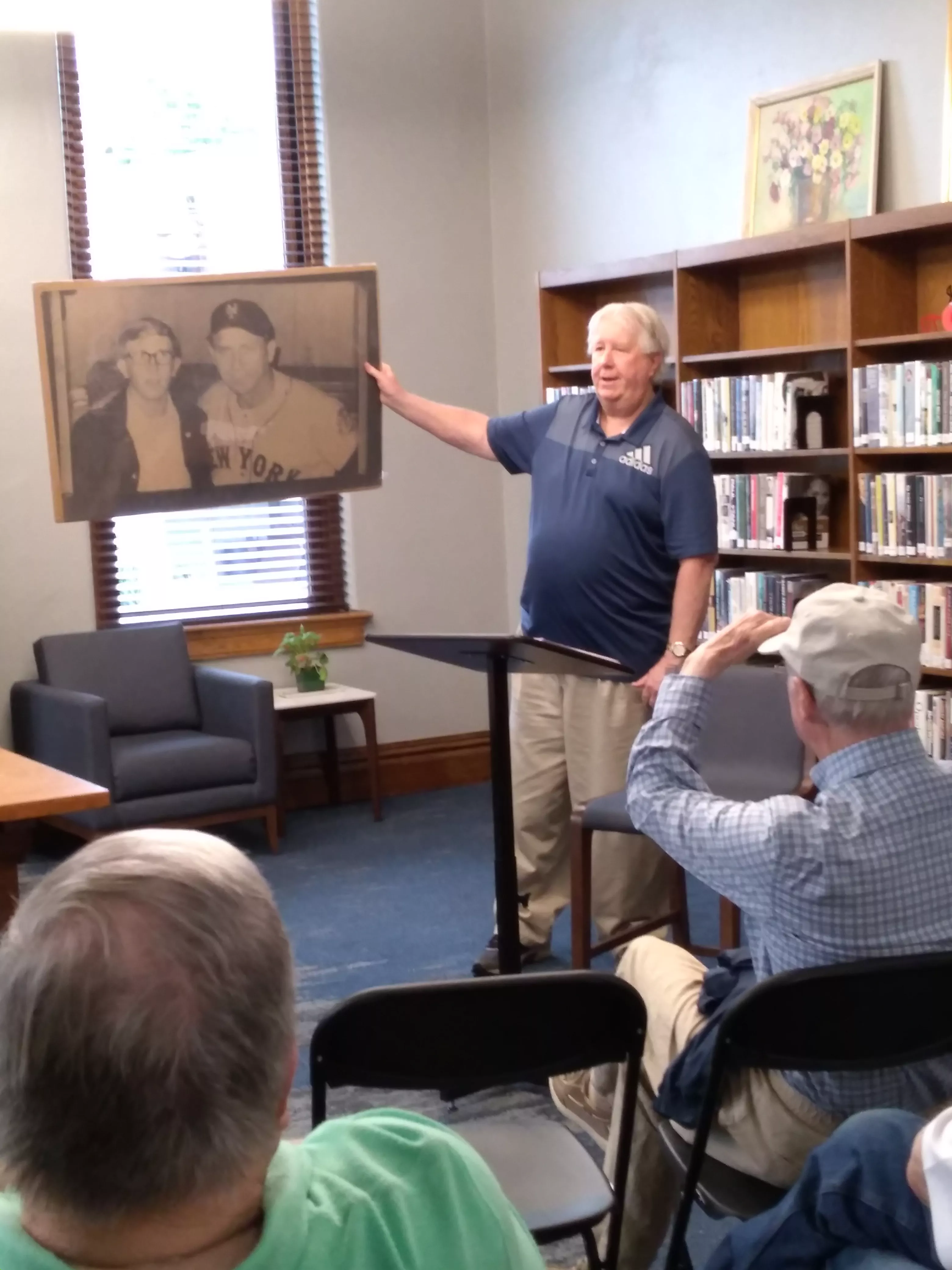 man holds photo of different man posing with baseball player Gil Hodges