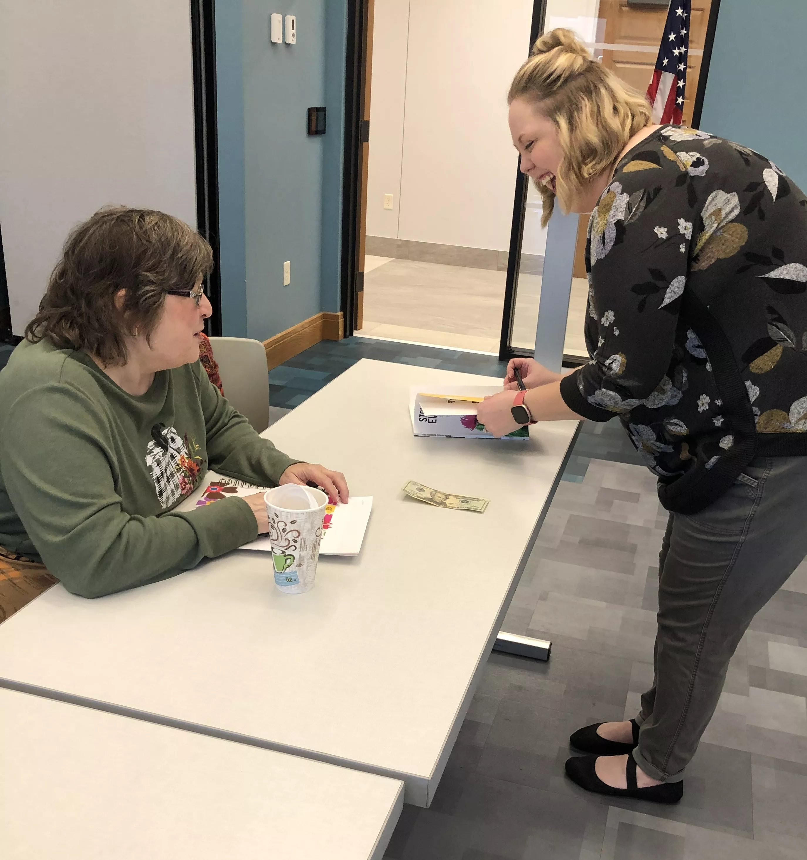 lady has woman sign a book